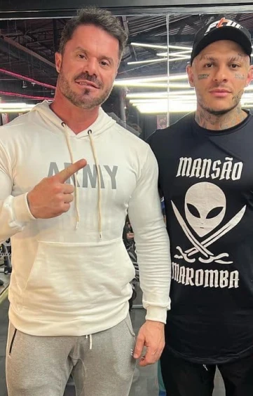 Homem com camiseta preta e outro com moletom branco no plano V-Shape.